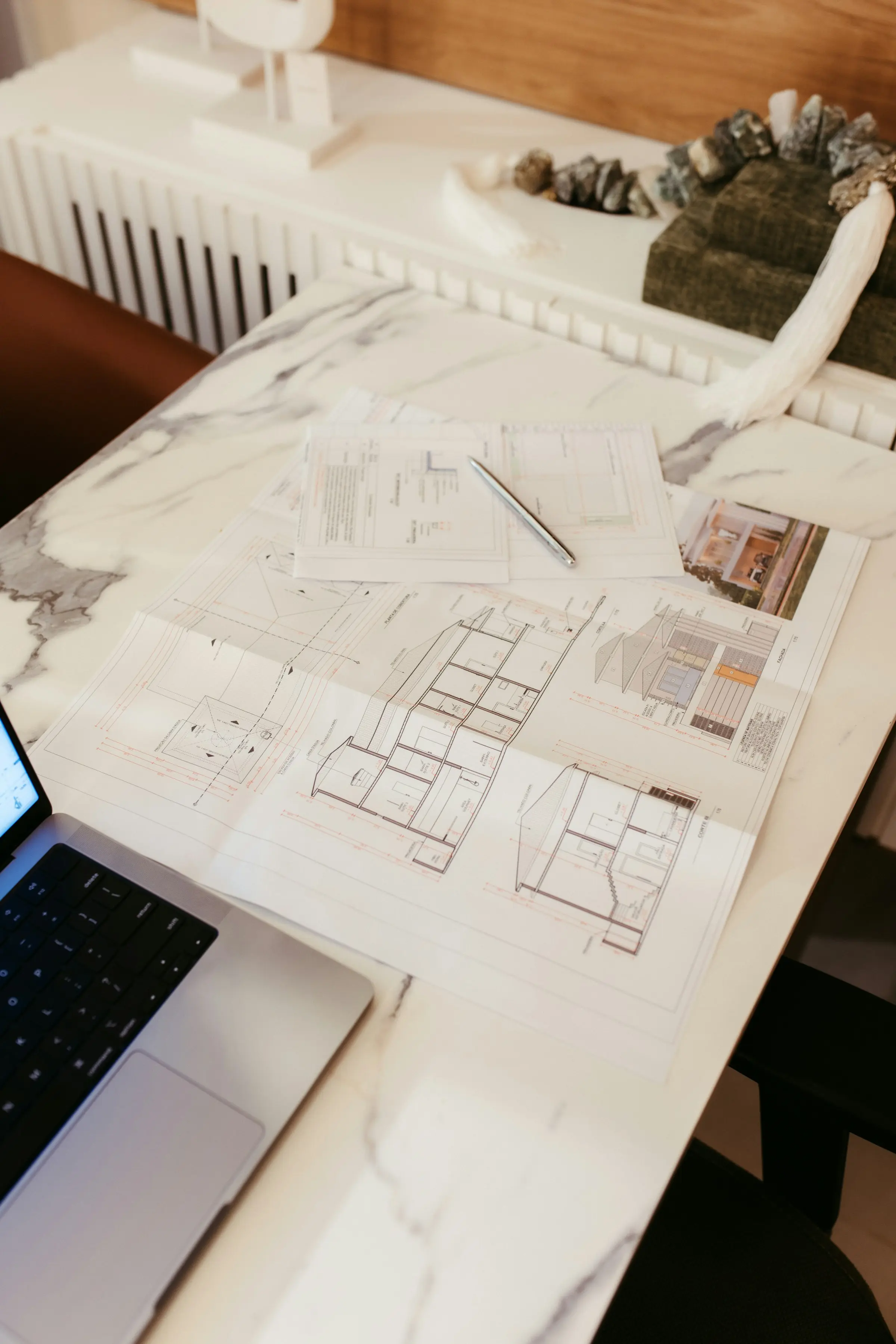 Plans d’aménagement, échantillons et ordinateur portable posés sur un bureau en marbre