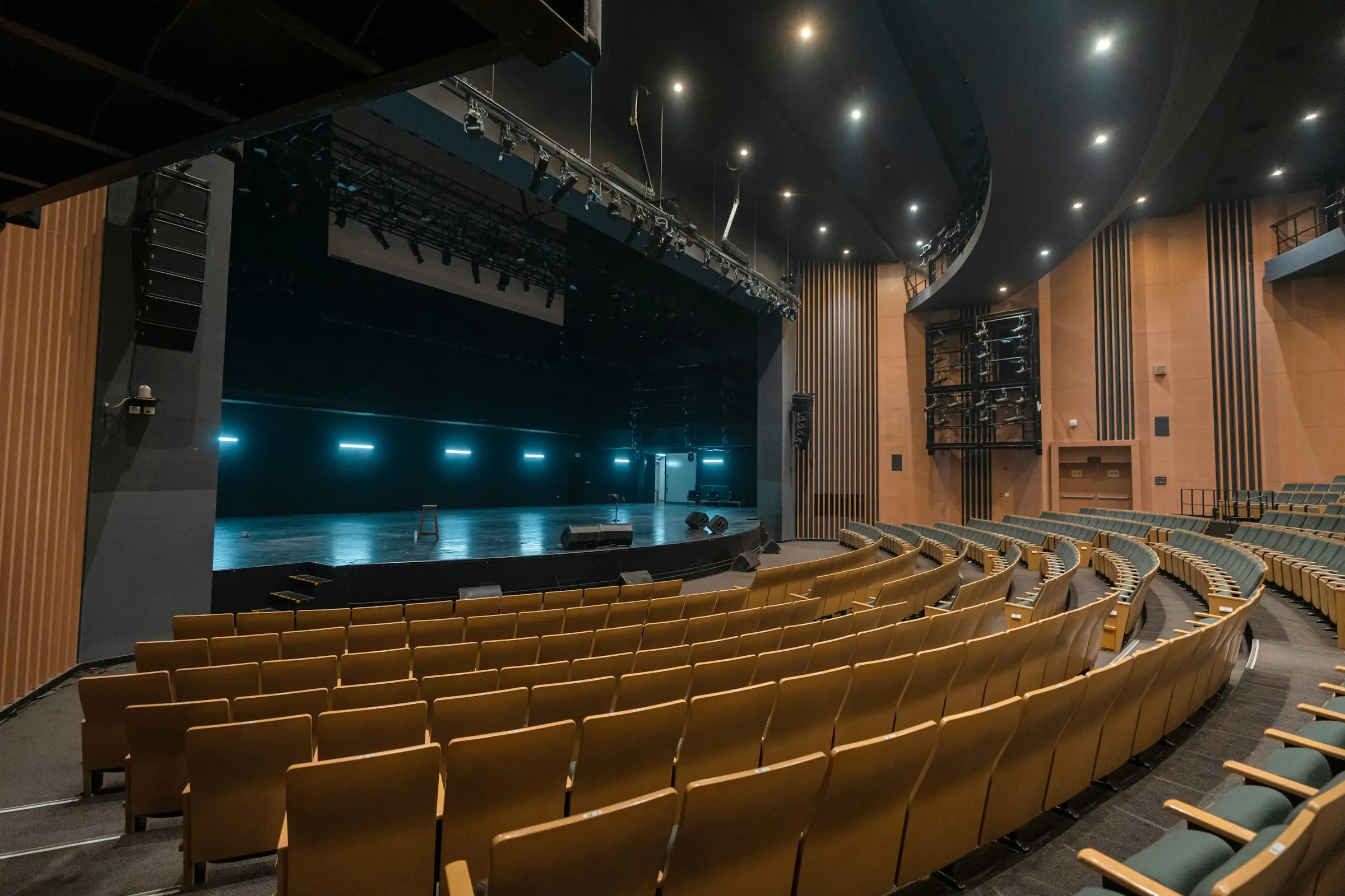 Auditorium vide aux fauteuils de bois clair, scène éclairée de lumière bleutée