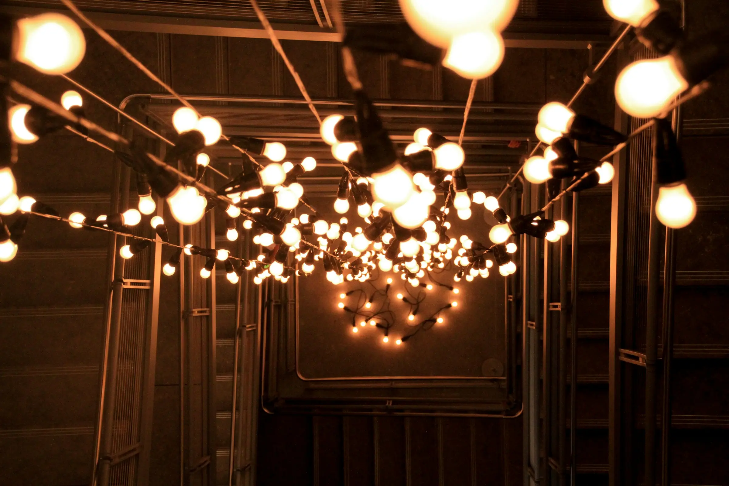 Installation de guirlandes d’ampoules suspendues dans un espace sombre